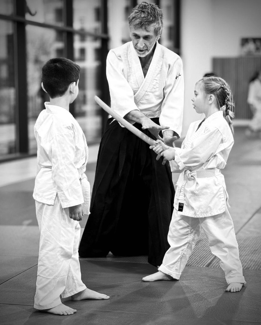 Un enseignant guide deux jeunes élèves au bokken