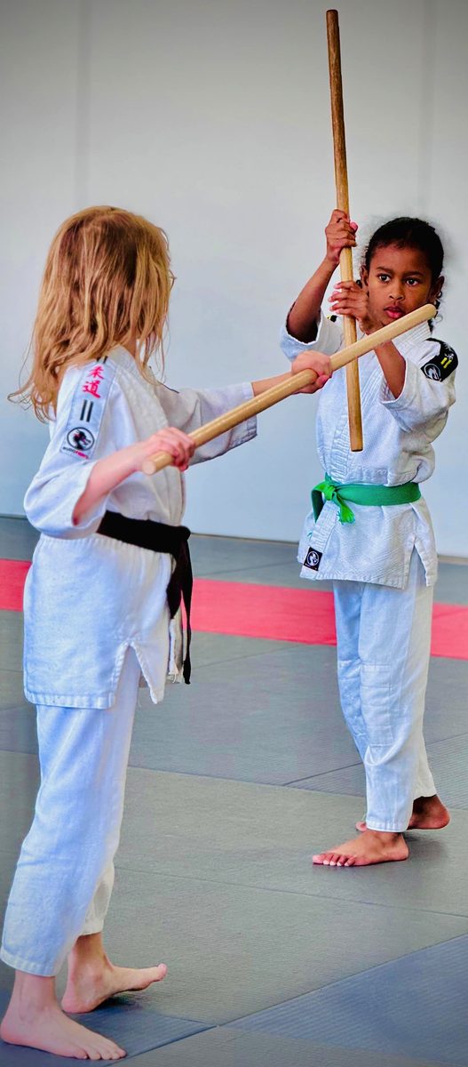 Jeune élève ceinture verte au bâton face à sa partenaire